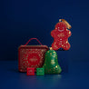 Godiva Christmas-themed chocolate packaging including a gingerbread man, bell, and tin on a blue background.